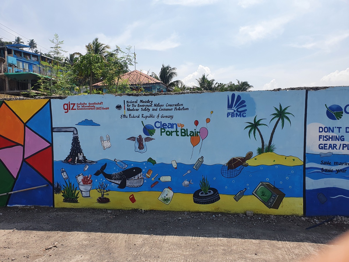 Gemälde an Wand mit Meer und Plastikmüll, darauf steht "Clean up Port Blair"
