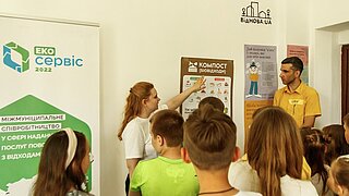 Kinder stehen vor Aufstellern, eine Frau erklärt