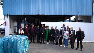 Gruppe des EXI-GIZ-Teams auf dem Gelände von ECO-LEF, im Vordergrund ein Ballen Plastik für das Recycling