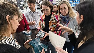 Personen stehen im Kreis und halten recyclebares Material in den Händen