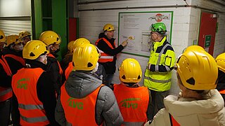 Eine Menschengruppe besichtigt ein Werk zur Abfallaufbereitung.