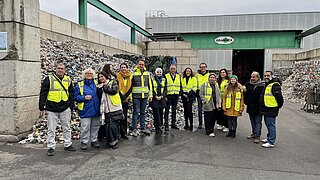 Gruppe von rund 15 Personen steht vor Recyclingunternehmen