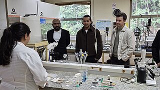 Mehrere Personen stehen bei einer Besichtigung in einem Labor. 