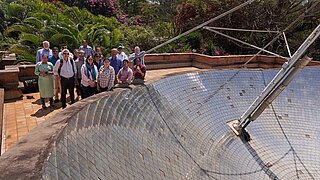 Teilnehmende stehen um eine große Solarschüssel auf einem Dach