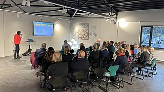 Frau hält Vortrag vor sitzender Personengruppe