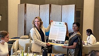 Bundesministerin Steffi Lemke und H D Varalaxmi von der Umweltschutzbehörde Chennai (CPCB) halten ein Poster zur deutsch-indischen Kooperation zur Entwicklung von Umweltstandards in der Textilindustrie