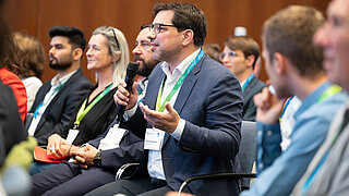 Mann in Publikum spricht in Mikro