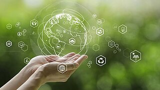 zwei Hände halten eine Weltkugel in der Hand, daneben einige Symbole aus dem Umweltschutz und von Umwelttechnologien