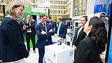 Carsten Schneider lächelt an Stand mit Wasserzähler als Exponat, um ihn herum stehen weitere Personen