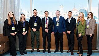 Gruppenfoto von 8 Personen in formeller Kleidung