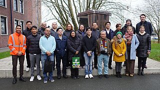 Eine Menschengruppe steht in einer städtischen Umgebung vor der Kamera.