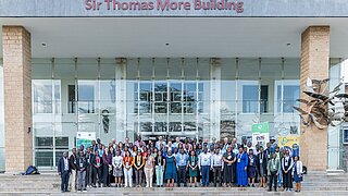 Gruppenbild mit rund 60 Personen vor Sir Thomas More Building