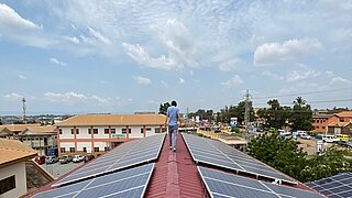 ein Mann läuft über ein Dach mit Solarpanelen