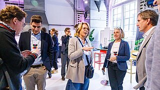 zwei Frauen und drei Männer stehen im Kreis und tauschen sich aus