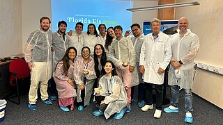 Gruppenfoto von 14 Menschen in Schutzanzügen vor Leinwand mit dem Logo von Florida Eis