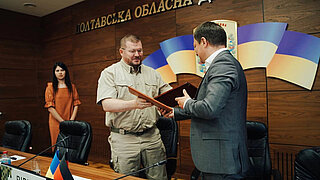 Dmytro Lunin, Leiter der Militärverwaltung der Region Poltawa (links) und Taras Zhuravel, GIZ-Projektleiter (rechts) beim offiziellen Treffen zur Unterzeichnung der Kooperationsvereinbarung