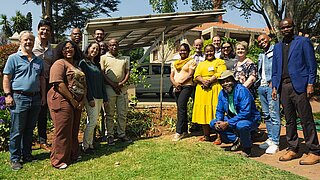 Gruppe aus Projektteilnehmenden und Partnern steht neben dem gepflanzten Baum