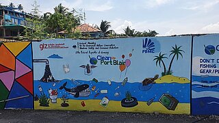 Gemälde an Wand mit Meer und Plastikmüll, darauf steht "Clean up Port Blair"