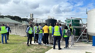 Menschen in Warnwesten besichtigen Pilotanlage in Kläranlage