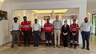 Gruppenfoto mit 8 Personen, teilweise in Arbeitskleidung