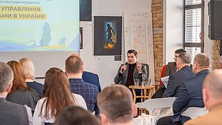 Zwei Personen sitzen auf einer Konferenz.