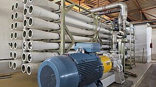 Große industrielle Anlage mit mehreren weißen Rohrbündeln und einem blauen Motor