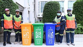 4 Arbeiter stehen neben Mülltonnen zur Mülltrennung